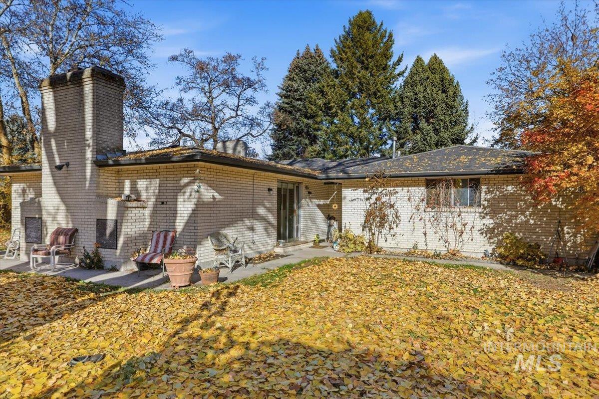 View of front of house featuring a chimney, brick siding, and a patio area