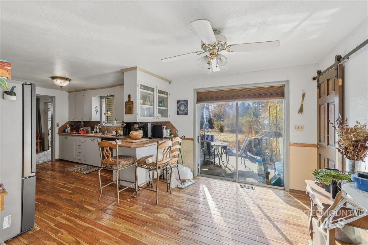 Dining space featuring a barn door, light wood-style flooring, and ceiling fan