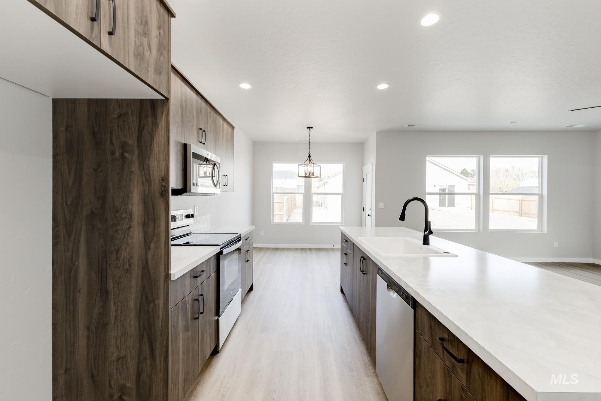 Kitchen featuring appliances with stainless steel finishes, light countertops, pendant lighting, modern cabinets, and recessed lighting
