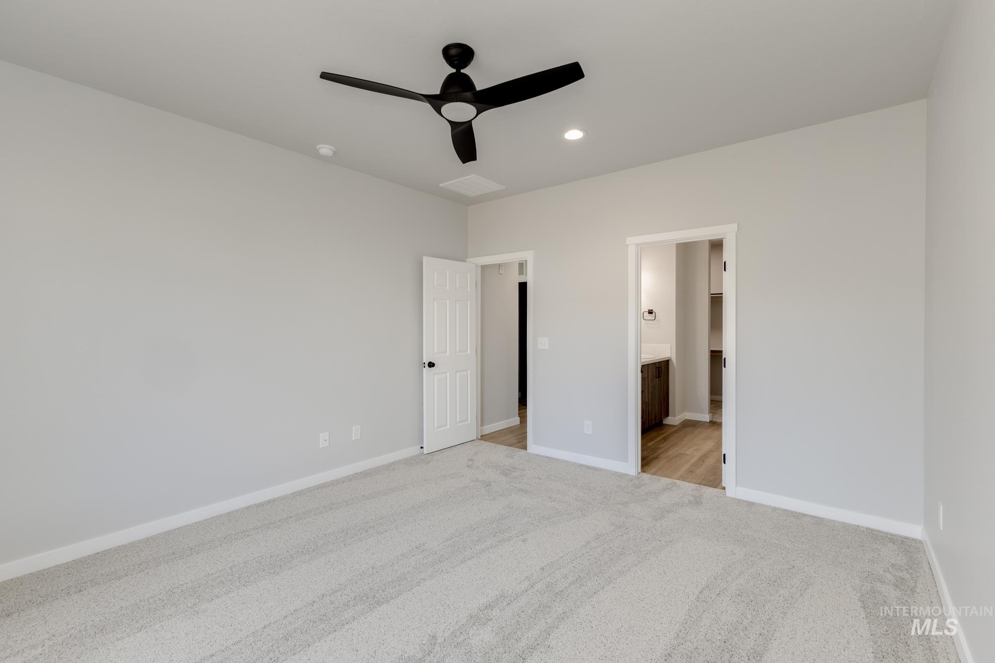 Unfurnished bedroom featuring light colored carpet, a ceiling fan, connected bathroom, and recessed lighting