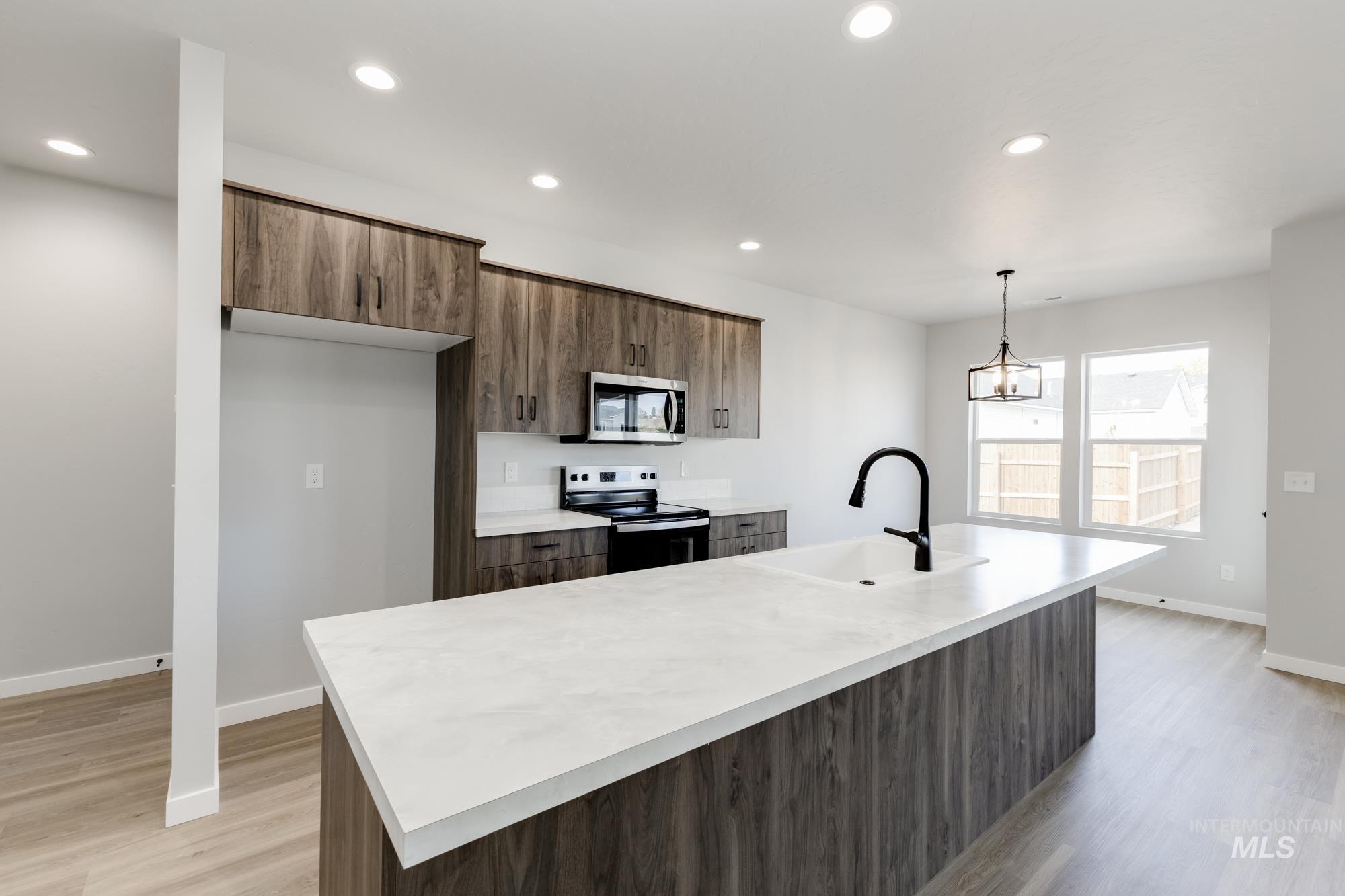 Kitchen featuring light countertops, appliances with stainless steel finishes, recessed lighting, an island with sink, and pendant lighting