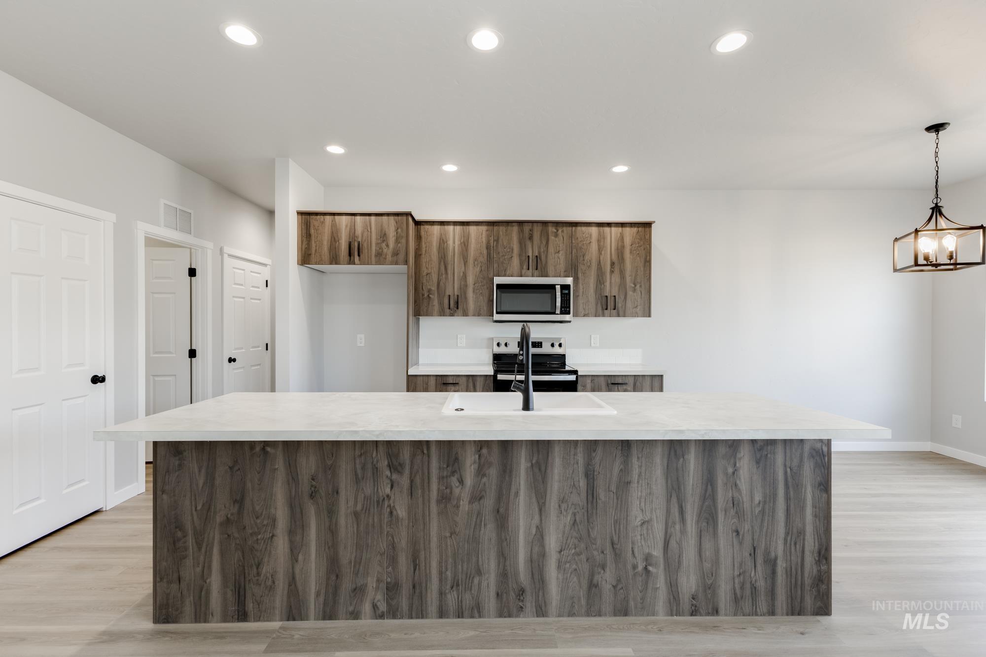 Kitchen featuring an island with sink, appliances with stainless steel finishes, recessed lighting, light wood-type flooring, and pendant lighting