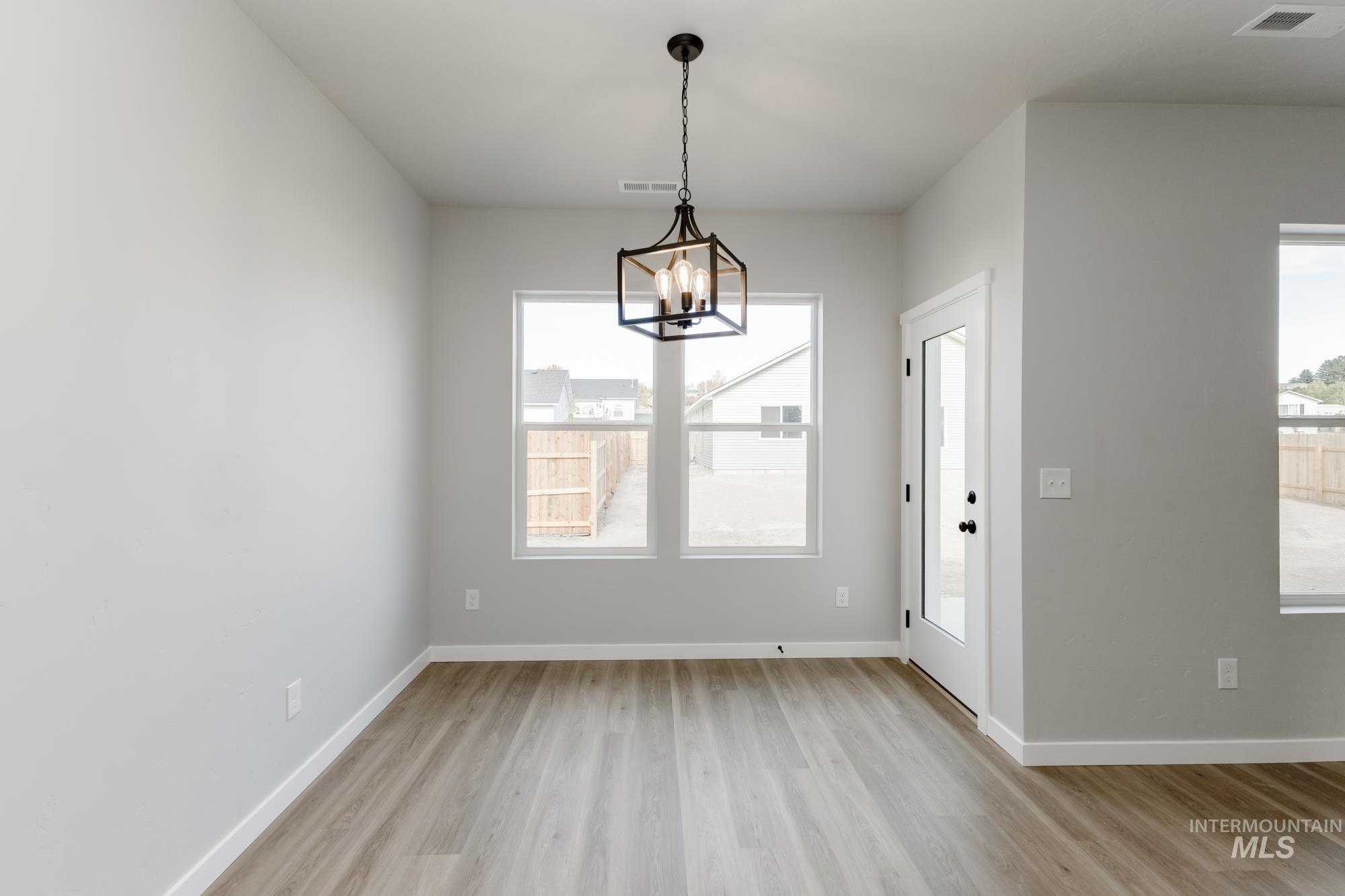 Unfurnished dining area with plenty of natural light, light wood-type flooring, and a chandelier