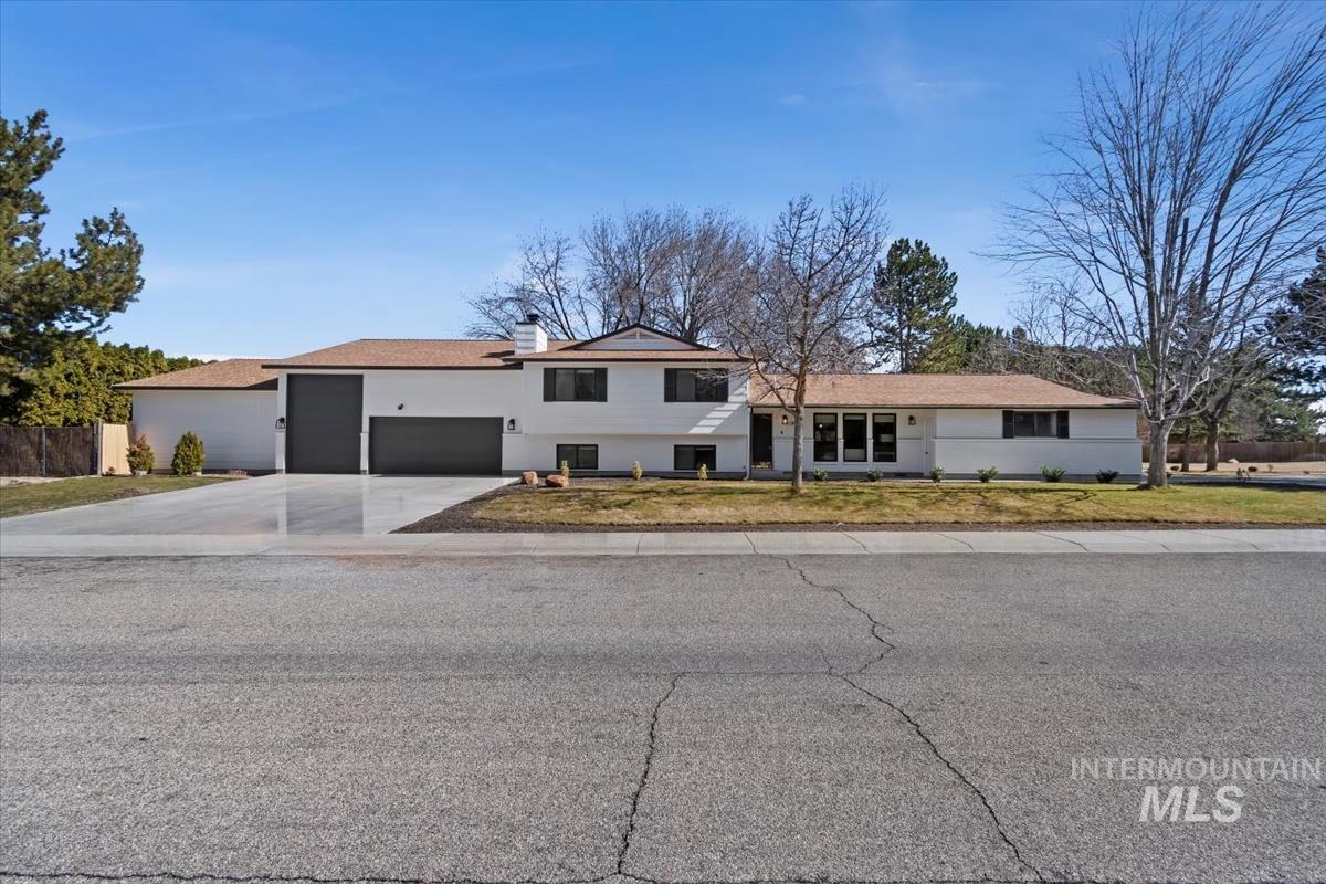 Tri-level home with a garage, driveway, a chimney, and stucco siding