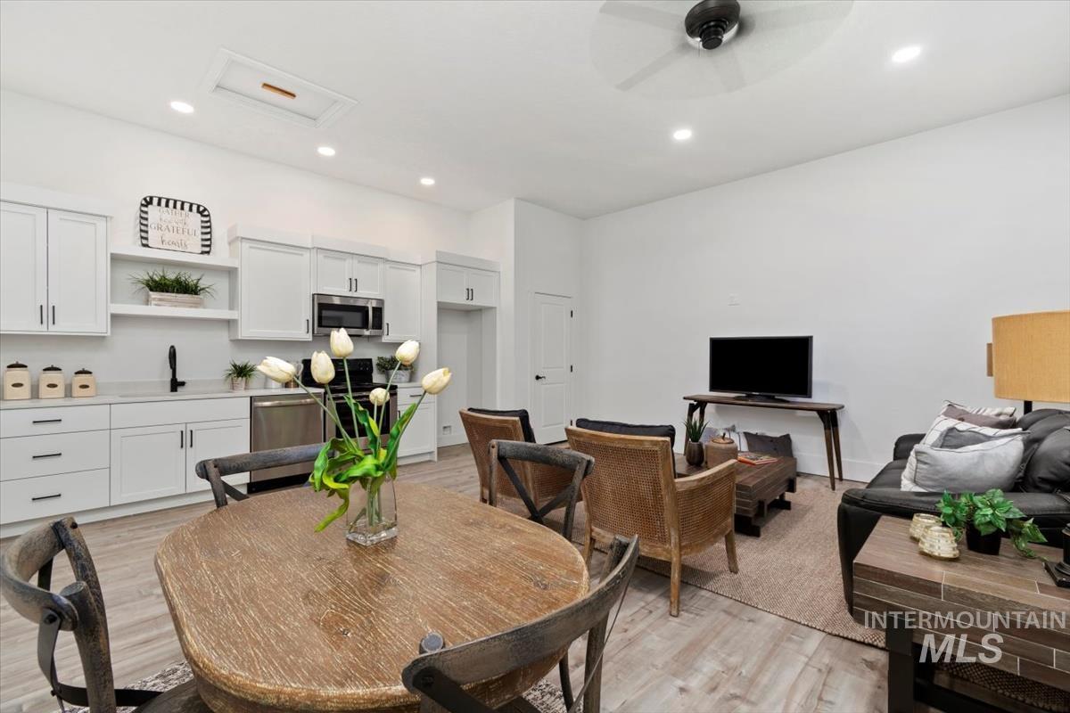 Dining space featuring light wood-style floors, a ceiling fan, attic access, and recessed lighting