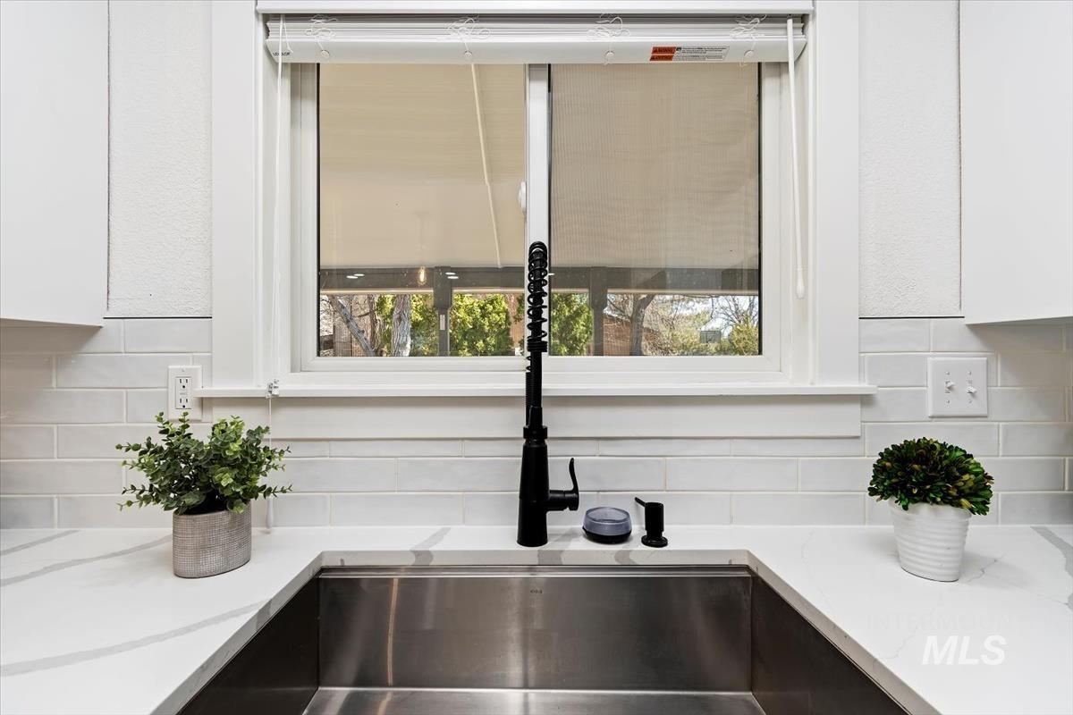 Kitchen view of white cabinets, tasteful backsplash, and light stone countertops