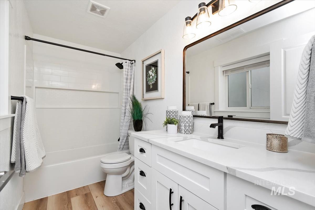 Bathroom with vanity, shower / tub combo, and wood finished floors
