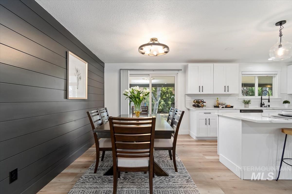 Dining room with light wood finished floors and wood walls