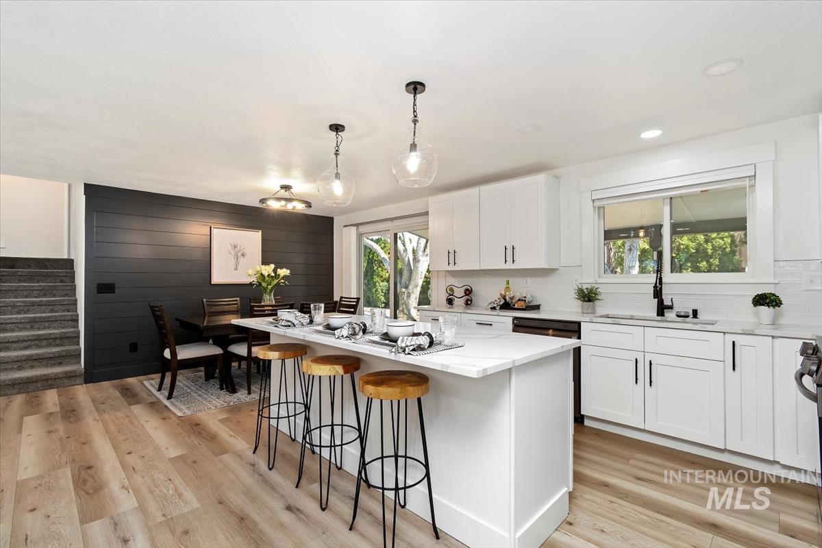 Kitchen featuring a breakfast bar area, white cabinetry, a center island, light wood-style floors, and pendant lighting