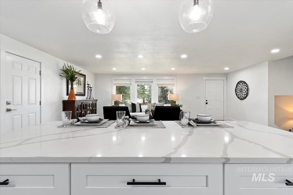 Kitchen with recessed lighting, white cabinets, light stone countertops, open floor plan, and pendant lighting