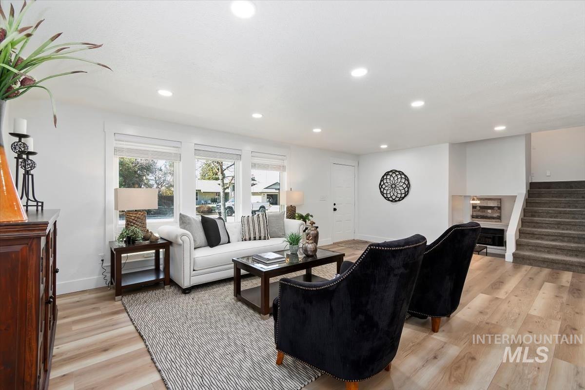 Living area with recessed lighting, stairs, and light wood-style floors
