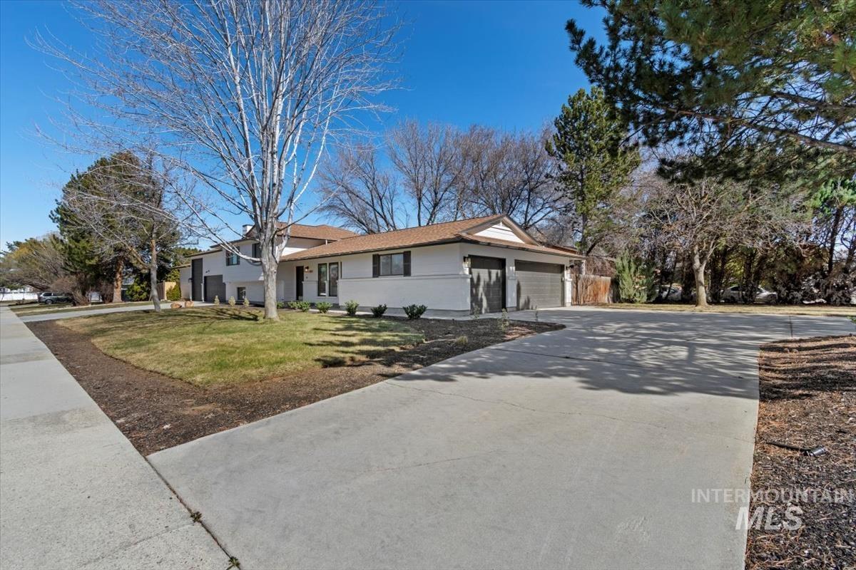View of front of property with an attached garage, concrete driveway, a front lawn, and stucco siding