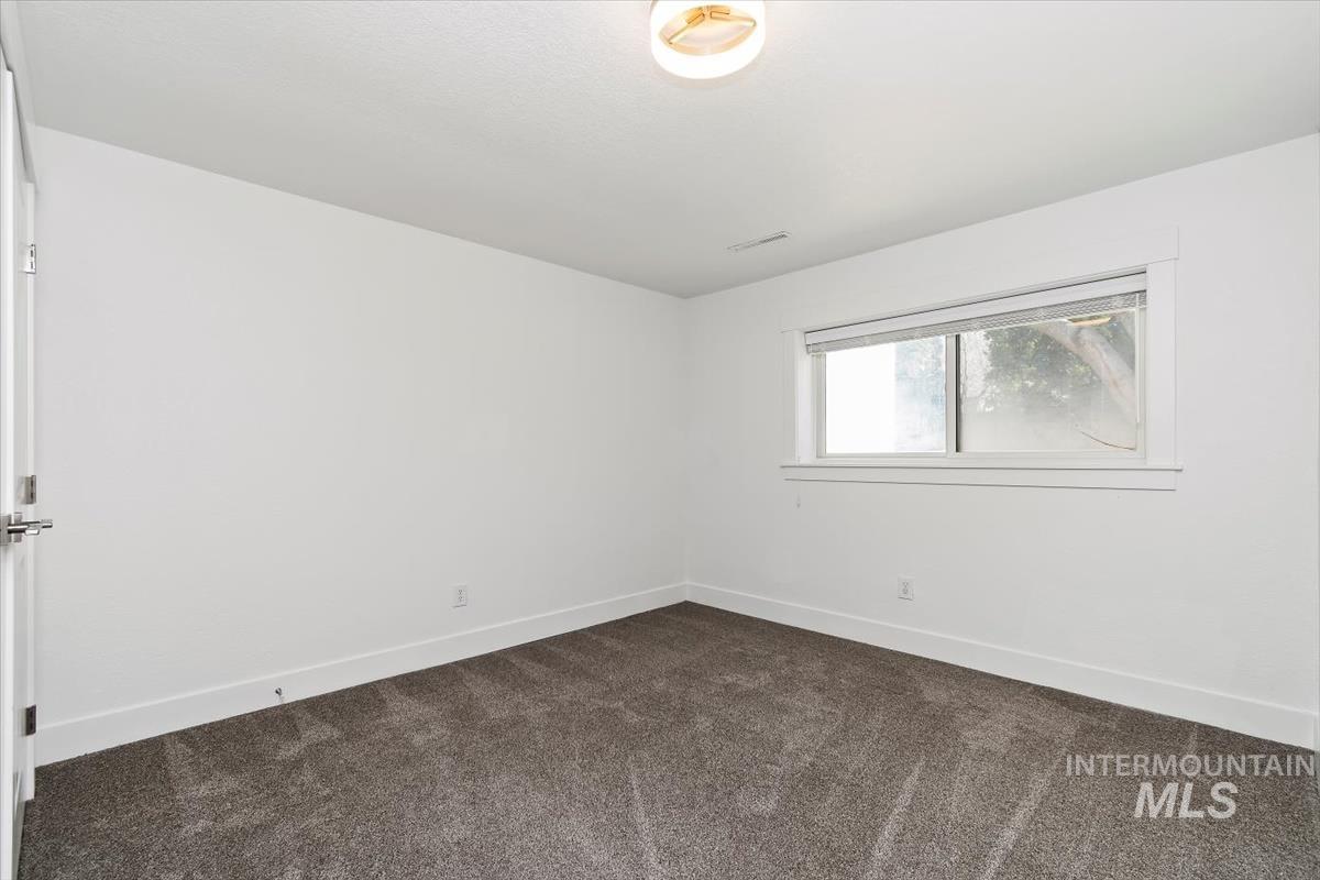 Spare room with dark colored carpet and baseboards