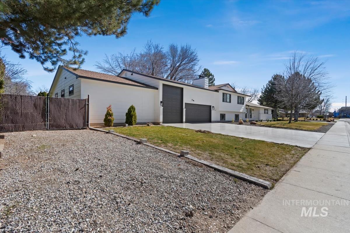 View of side of home featuring an attached garage, driveway, a chimney, and stucco siding