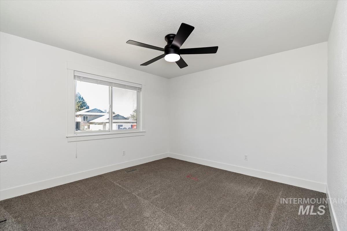 Unfurnished room with dark carpet and a ceiling fan