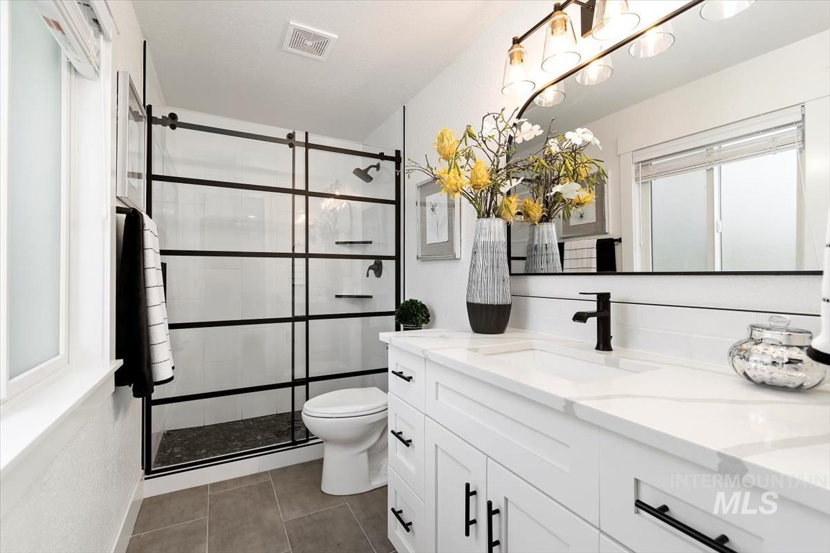 Bathroom featuring vanity, a shower stall, tile patterned flooring, and a chandelier