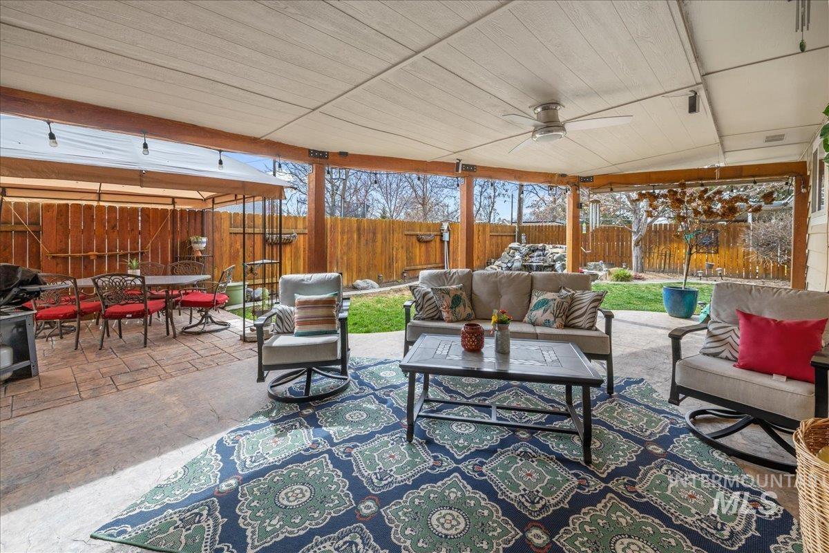 Fenced backyard with outdoor lounge area, a patio, and ceiling fan