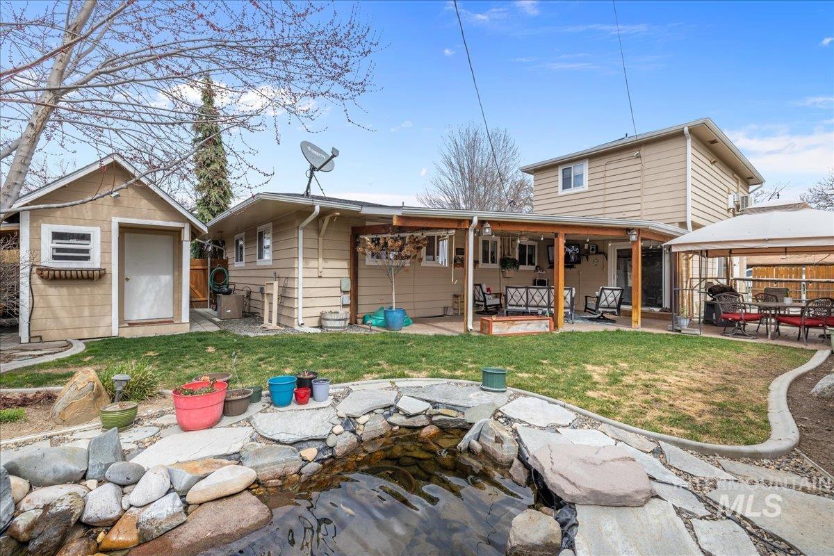 Back of house with a patio area, a storage shed, and a small pond