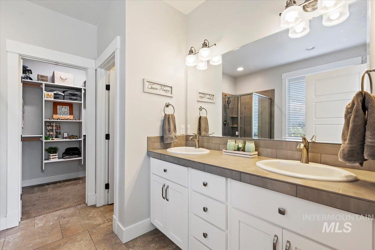 Bathroom featuring a stall shower, double vanity, a spacious closet, and recessed lighting