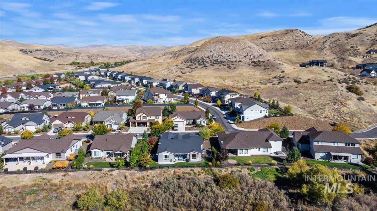 Aerial view of property and surrounding area featuring mountains and nearby suburban area