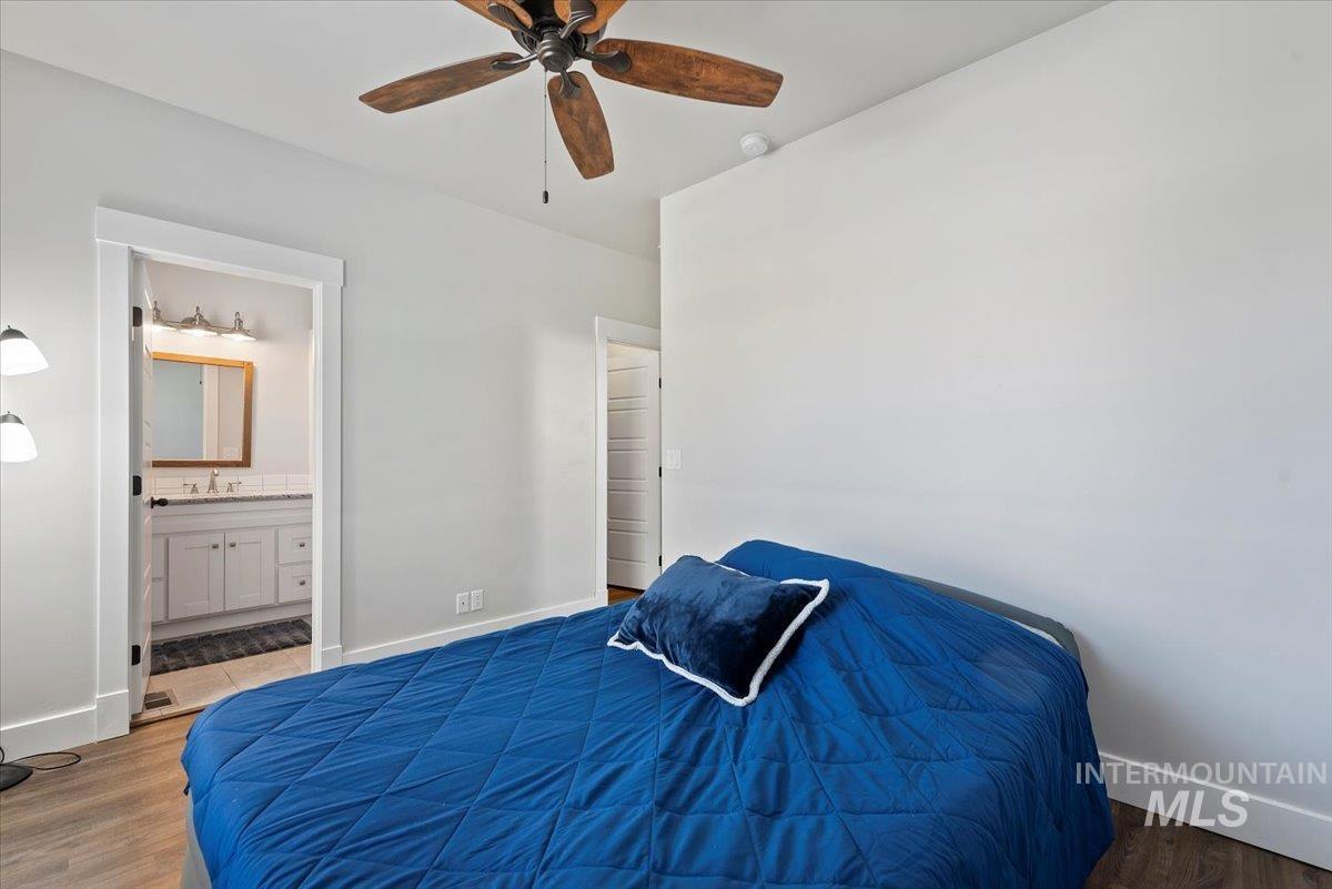 Bedroom with wood finished floors, a ceiling fan, and ensuite bath