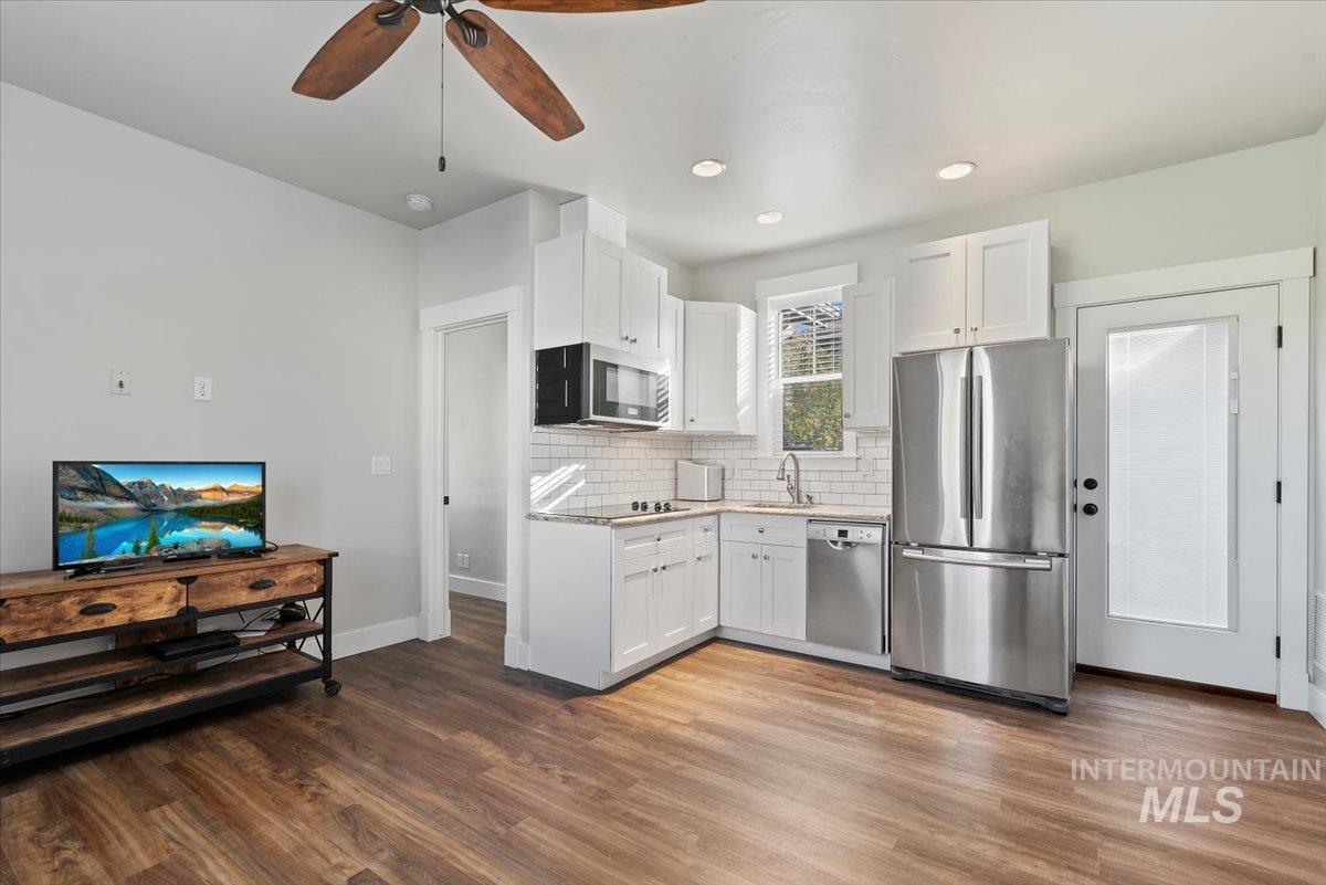 Kitchen featuring stainless steel appliances, white cabinetry, backsplash, dark wood-type flooring, and recessed lighting