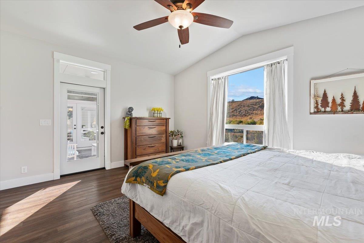 Bedroom with access to outside, vaulted ceiling, dark wood-style flooring, and ceiling fan