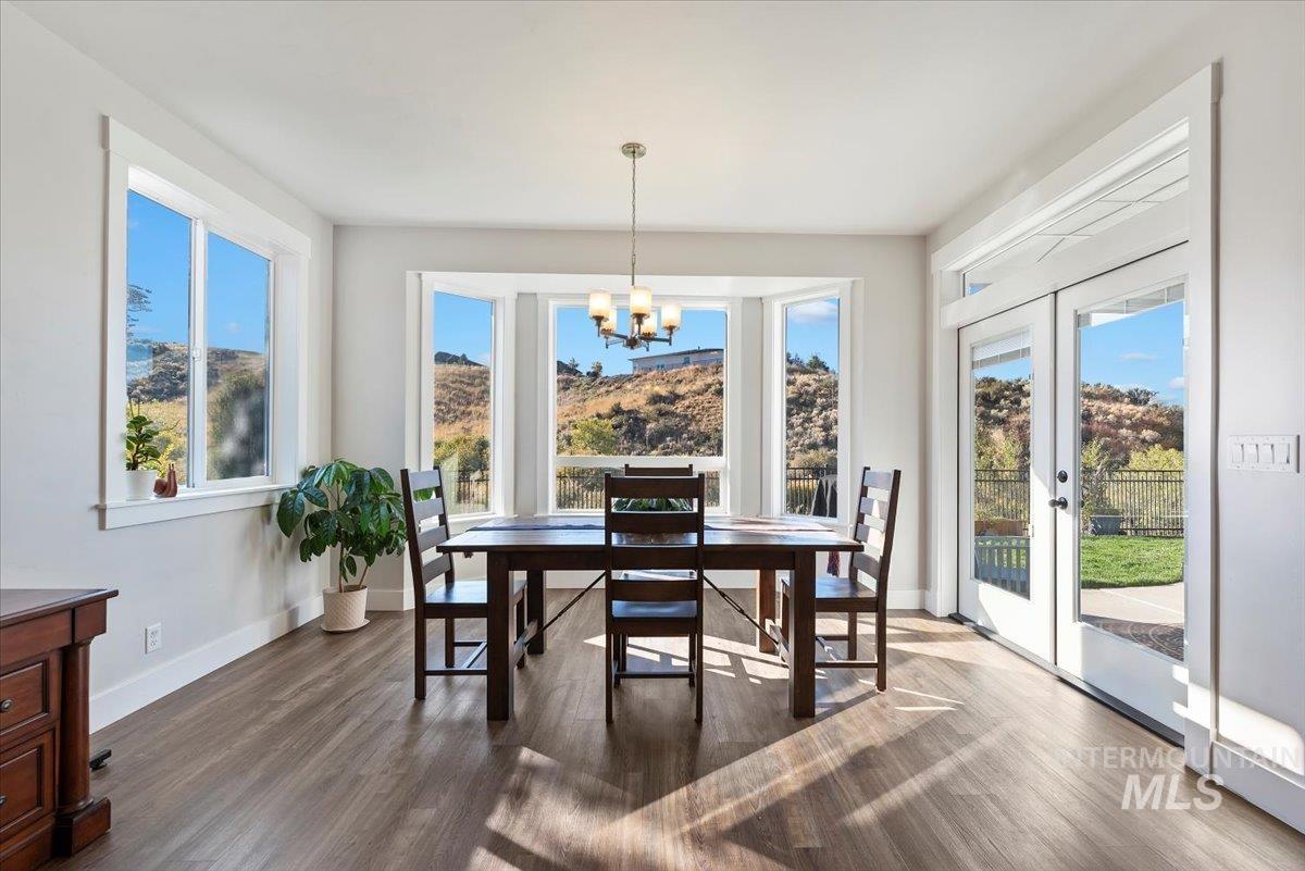Dining room with dark wood-style flooring, french doors, and a chandelier