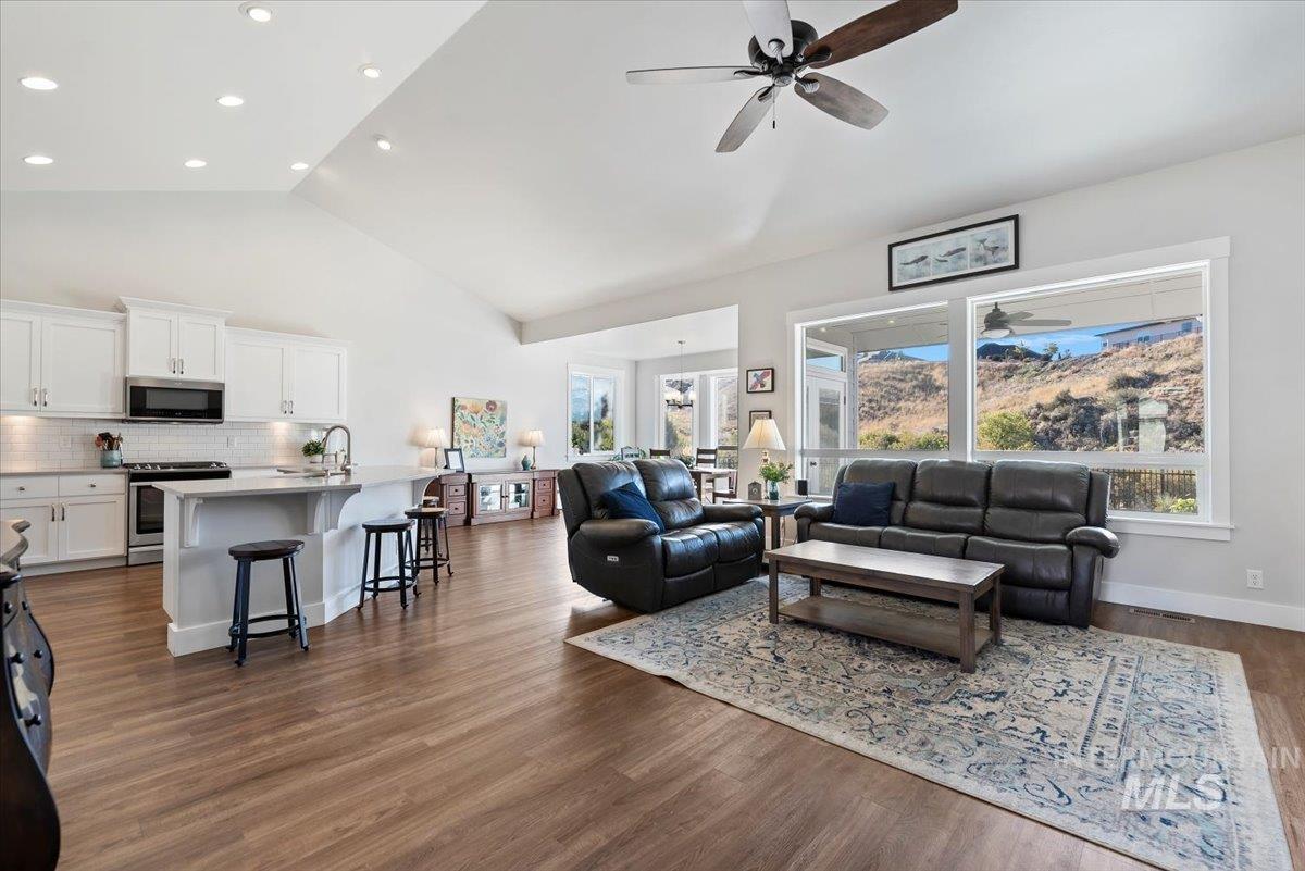 Living room with a ceiling fan, dark wood-type flooring, high vaulted ceiling, and recessed lighting