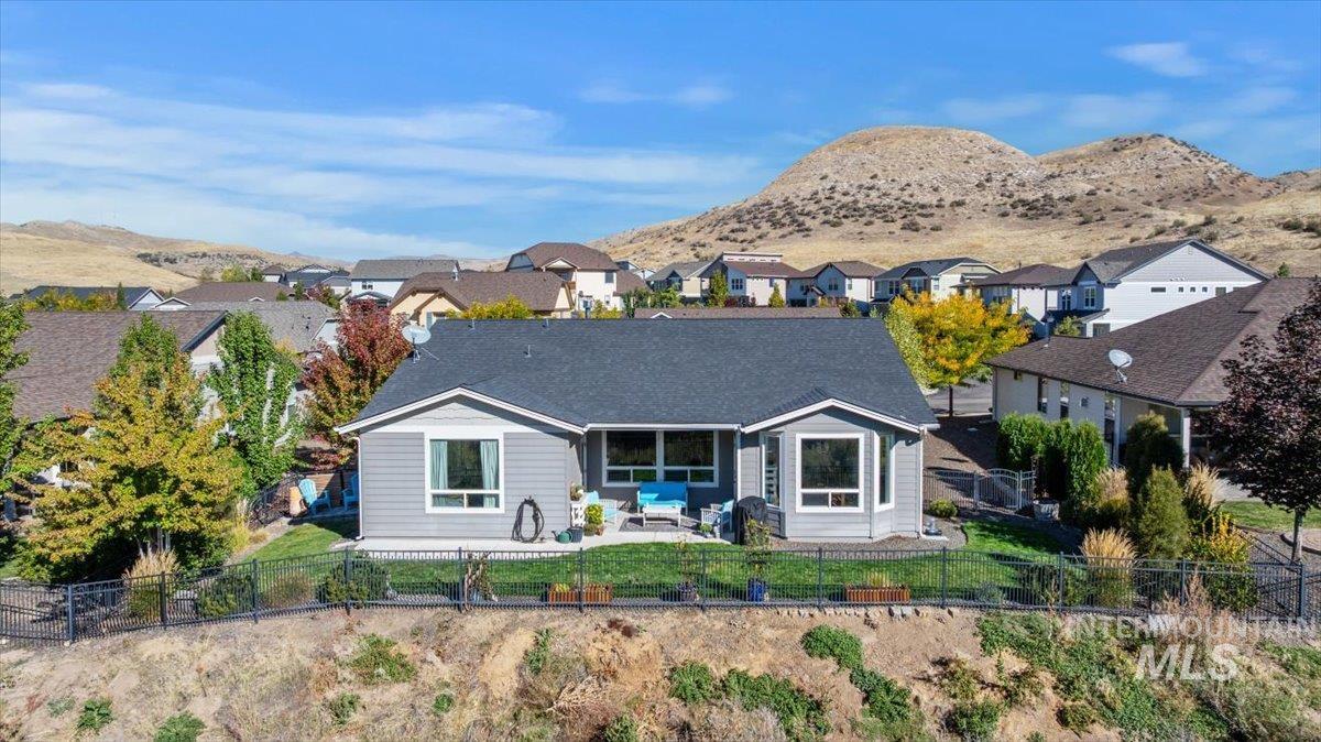 Rear view of property with a fenced backyard, a patio, a mountain view, and a residential view