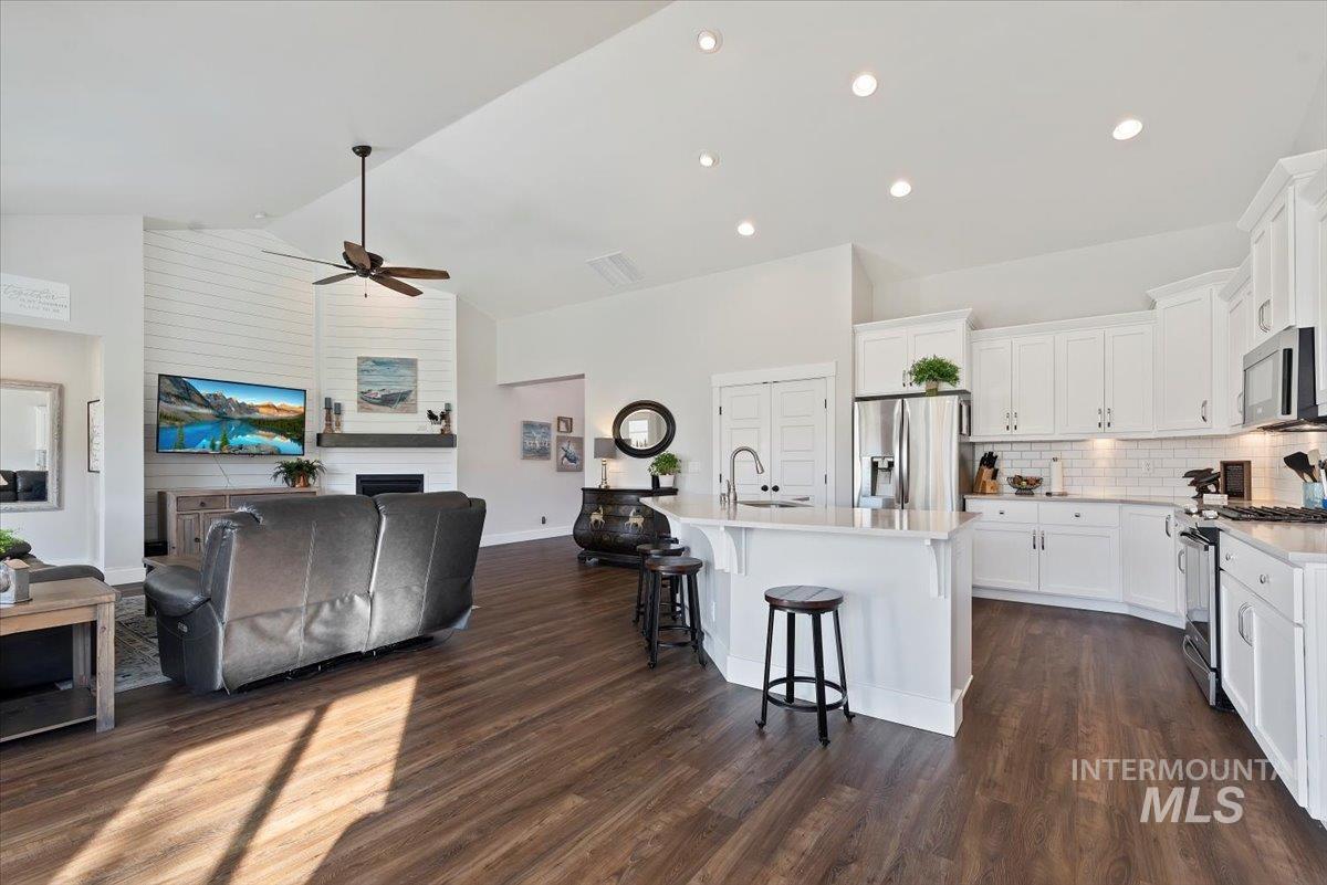 Kitchen with a breakfast bar, open floor plan, appliances with stainless steel finishes, a center island with sink, and white cabinets
