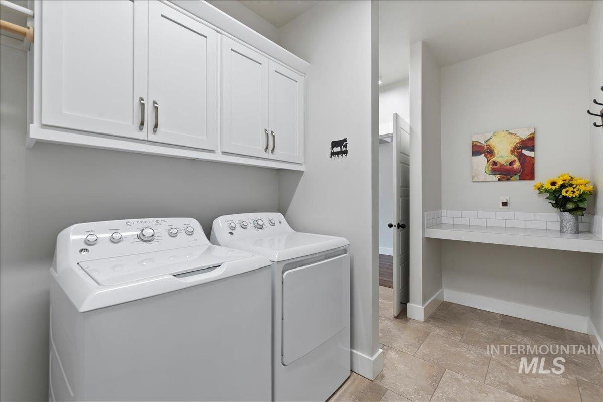 Laundry room featuring cabinet space, washing machine and dryer, and light stone finish flooring