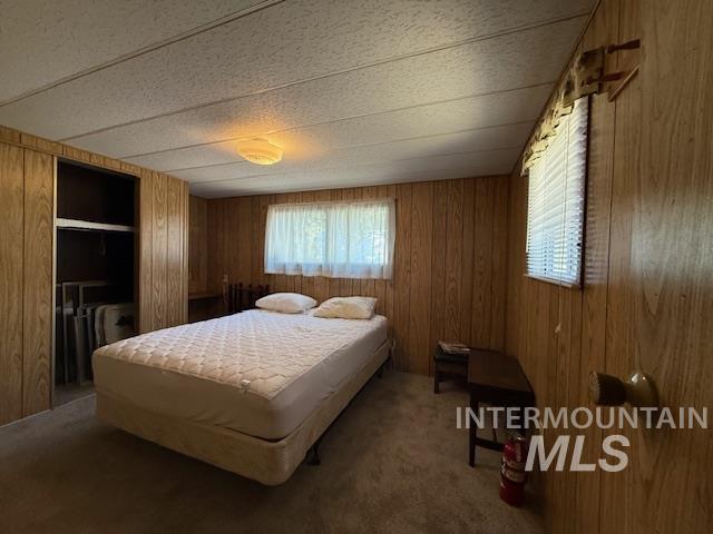 Bedroom with carpet flooring and wood walls