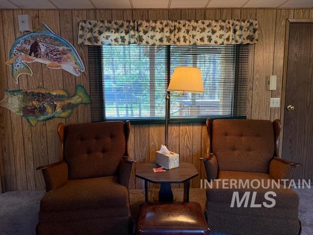 Sitting room with wooden walls, carpet flooring, and a paneled ceiling