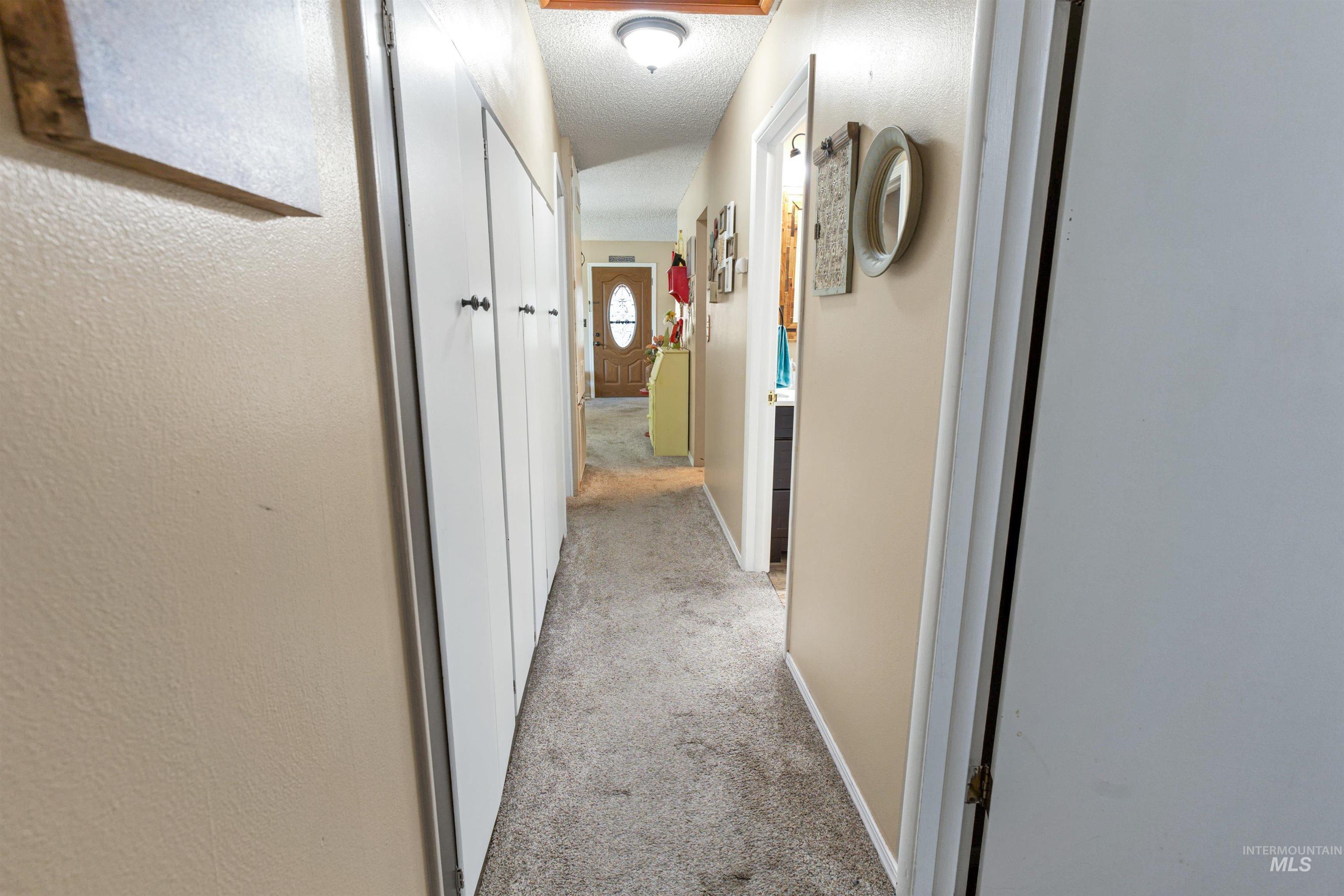 Interior hallway featuring neutral-toned walls and grey carpet flooring