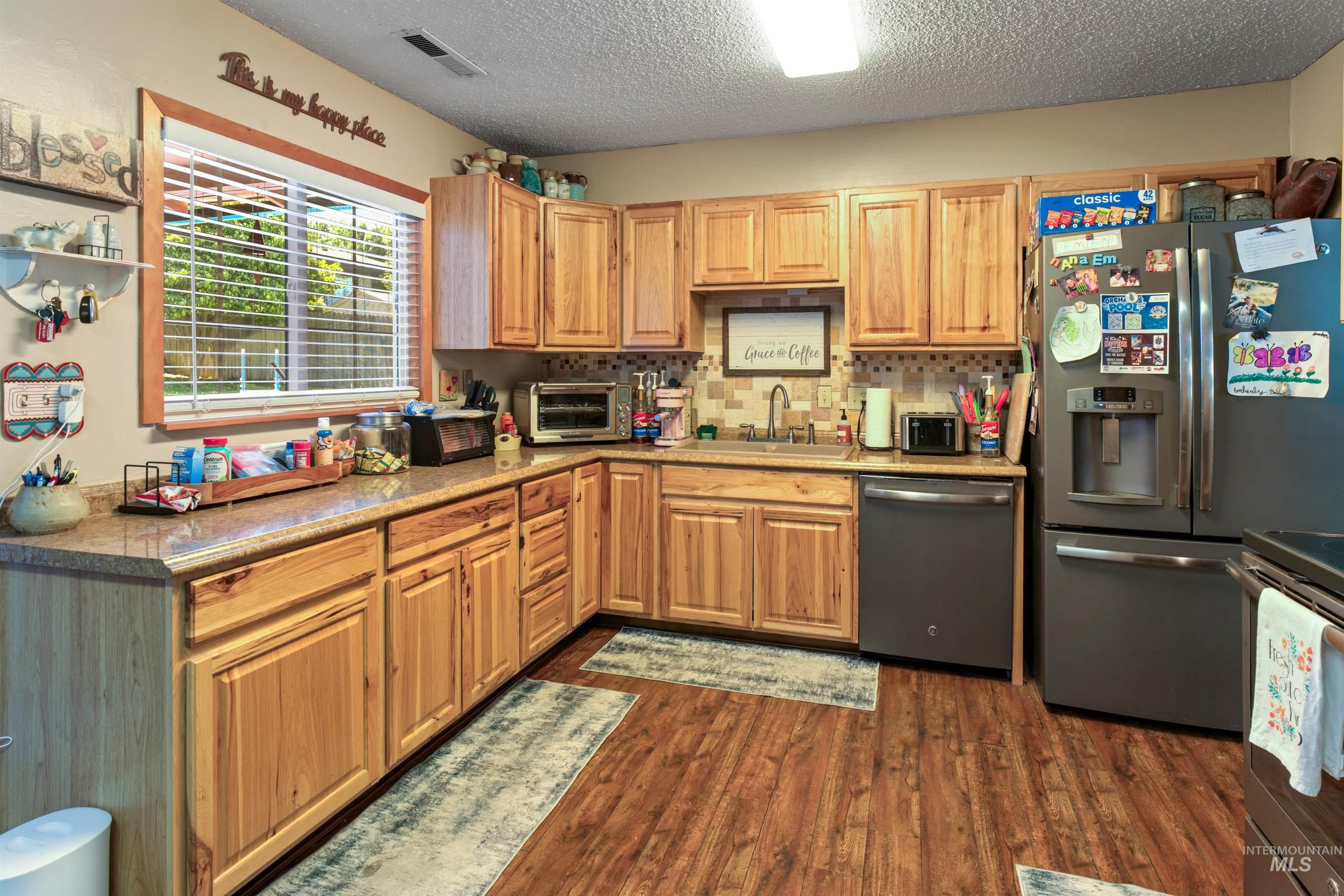 Kitchen featuring wood-finish flooring, wood cabinetry, and a stainless steel refrigerator