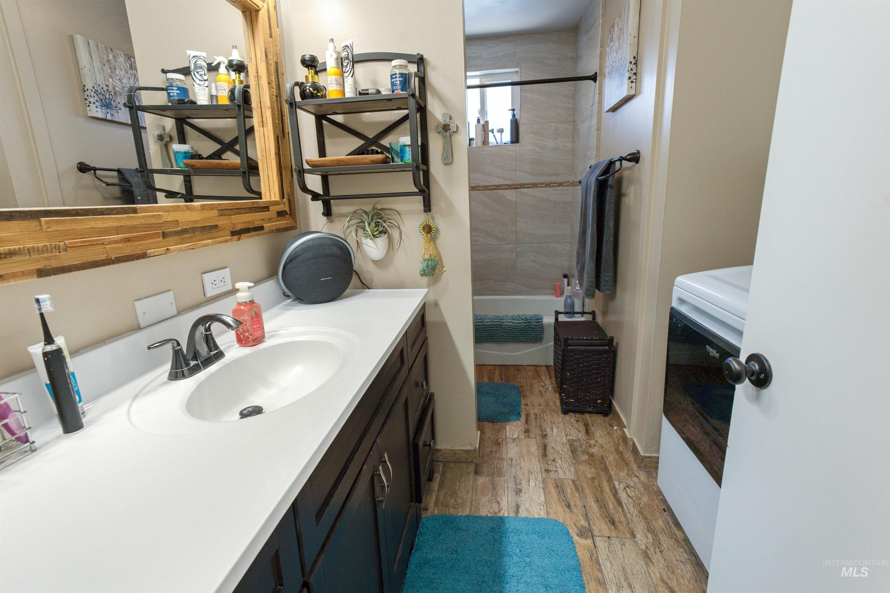 Bathroom featuring a vanity with an integrated sink, dark wood-finish cabinetry, black hardware, and wood-finish flooring