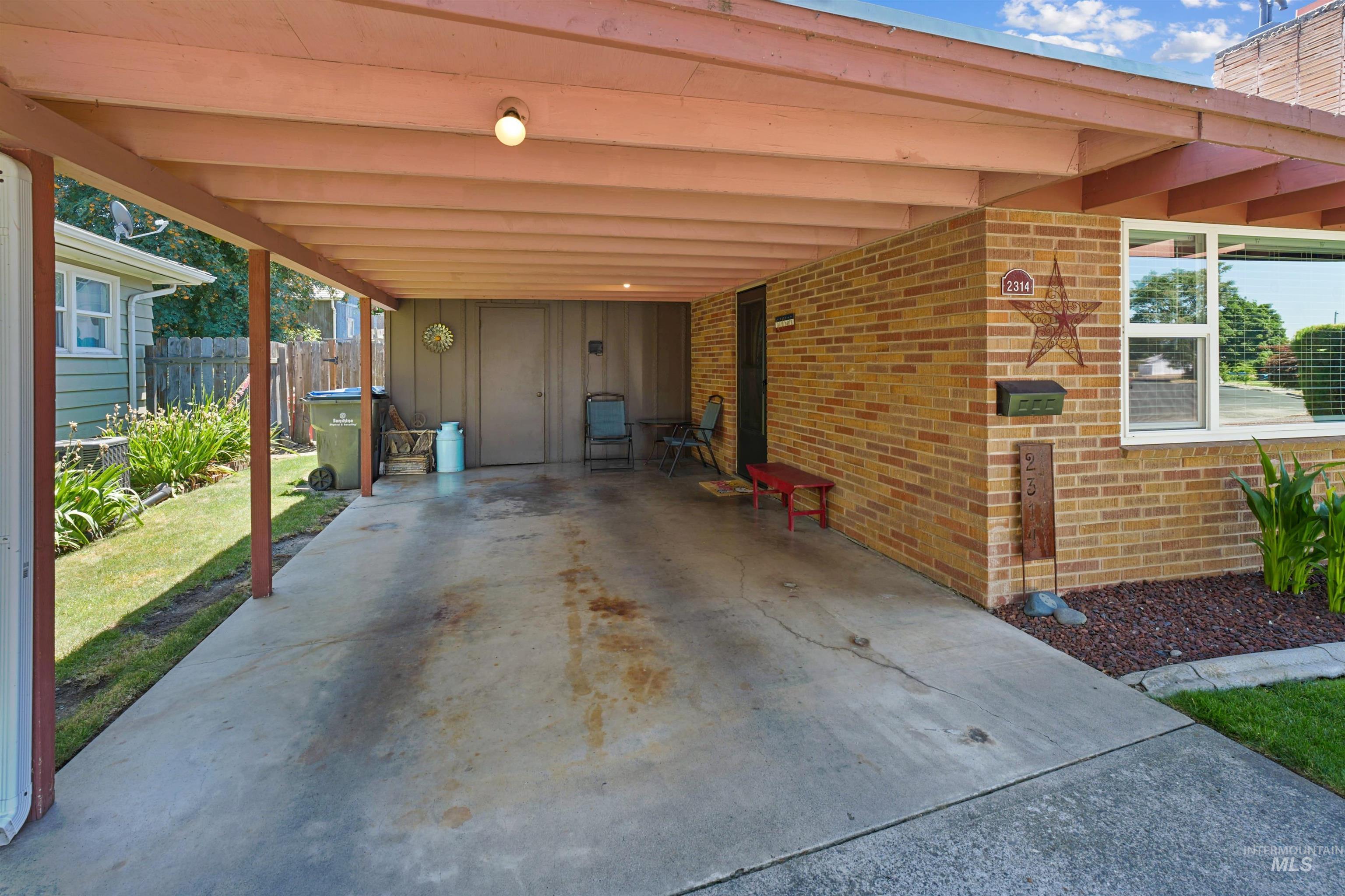 Carport featuring a concrete drive, brick exterior wall, and covered entry