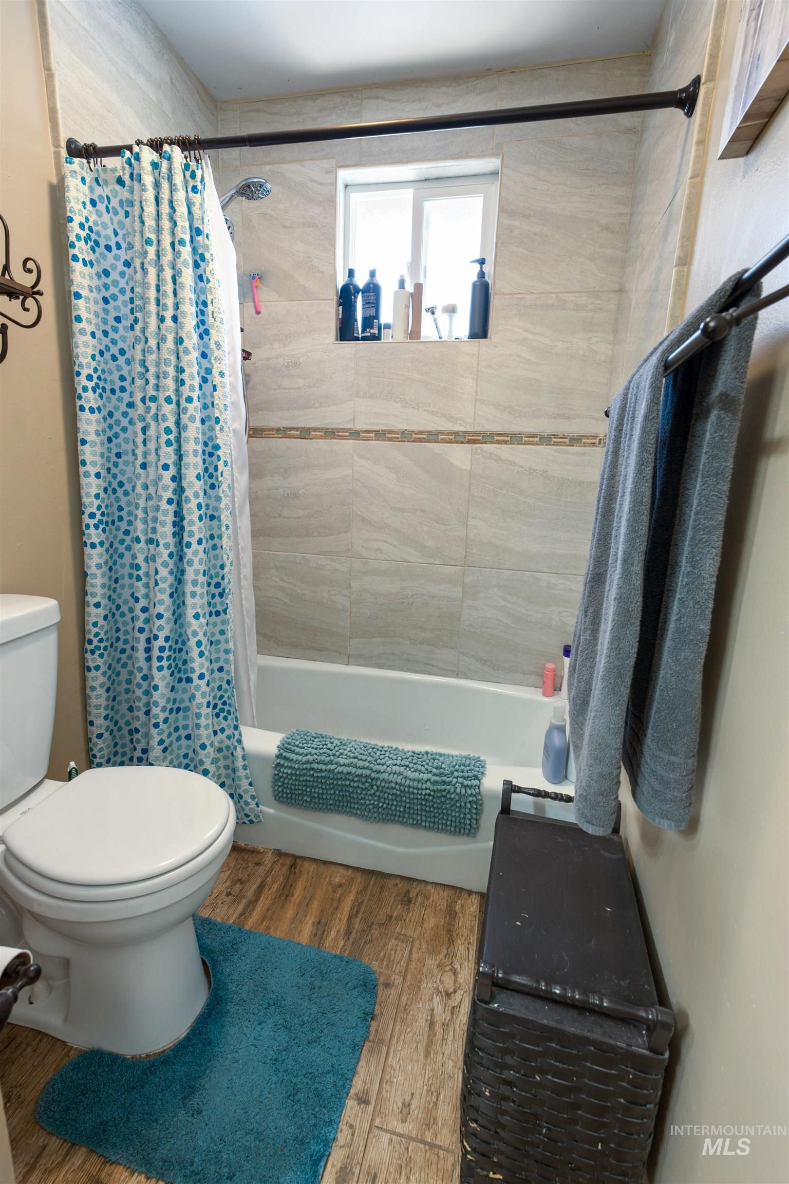 Shower/tub combination with light-toned tiled surround, accent border, and integrated window