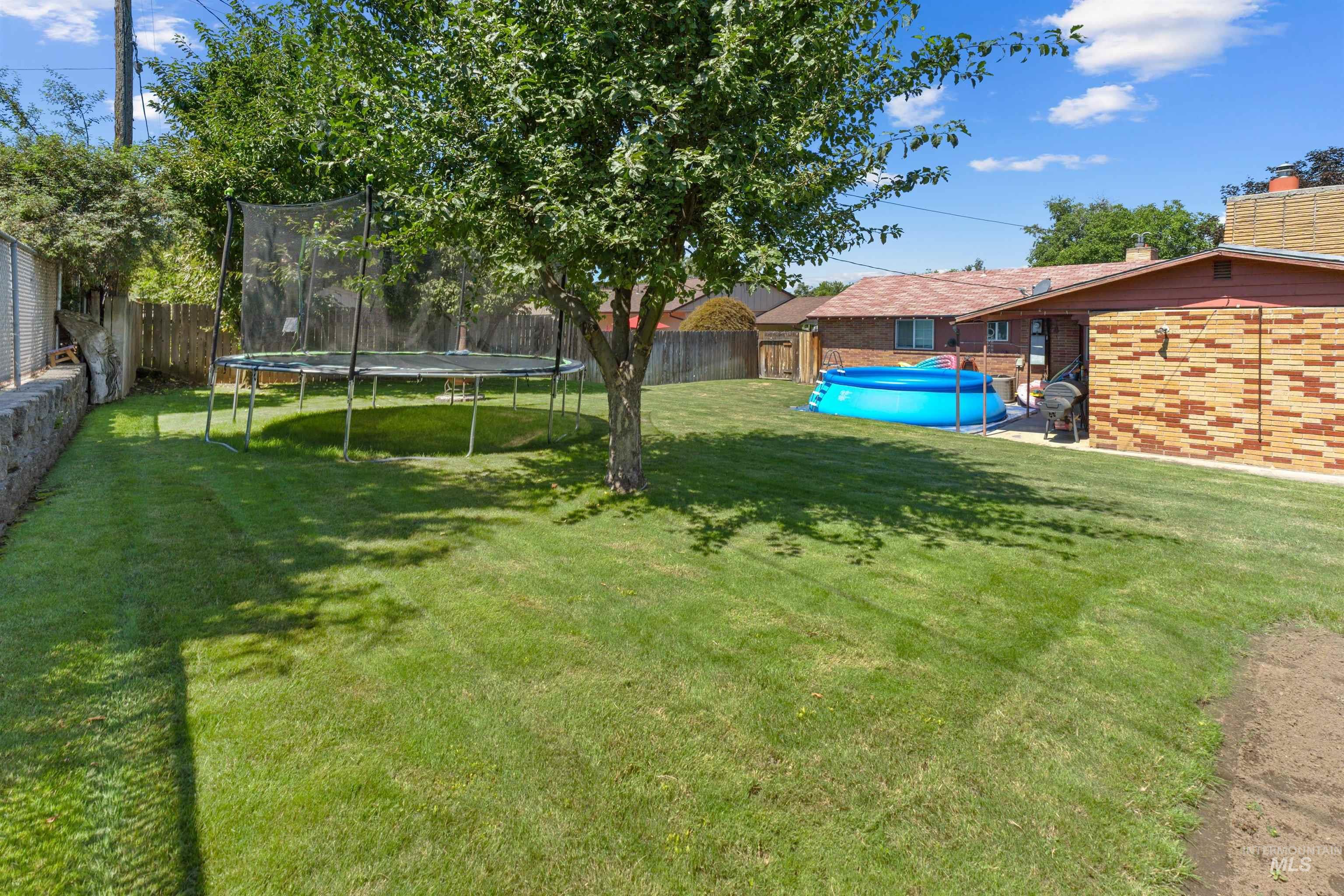 Expansive green lawn with mature trees and a fenced perimeter