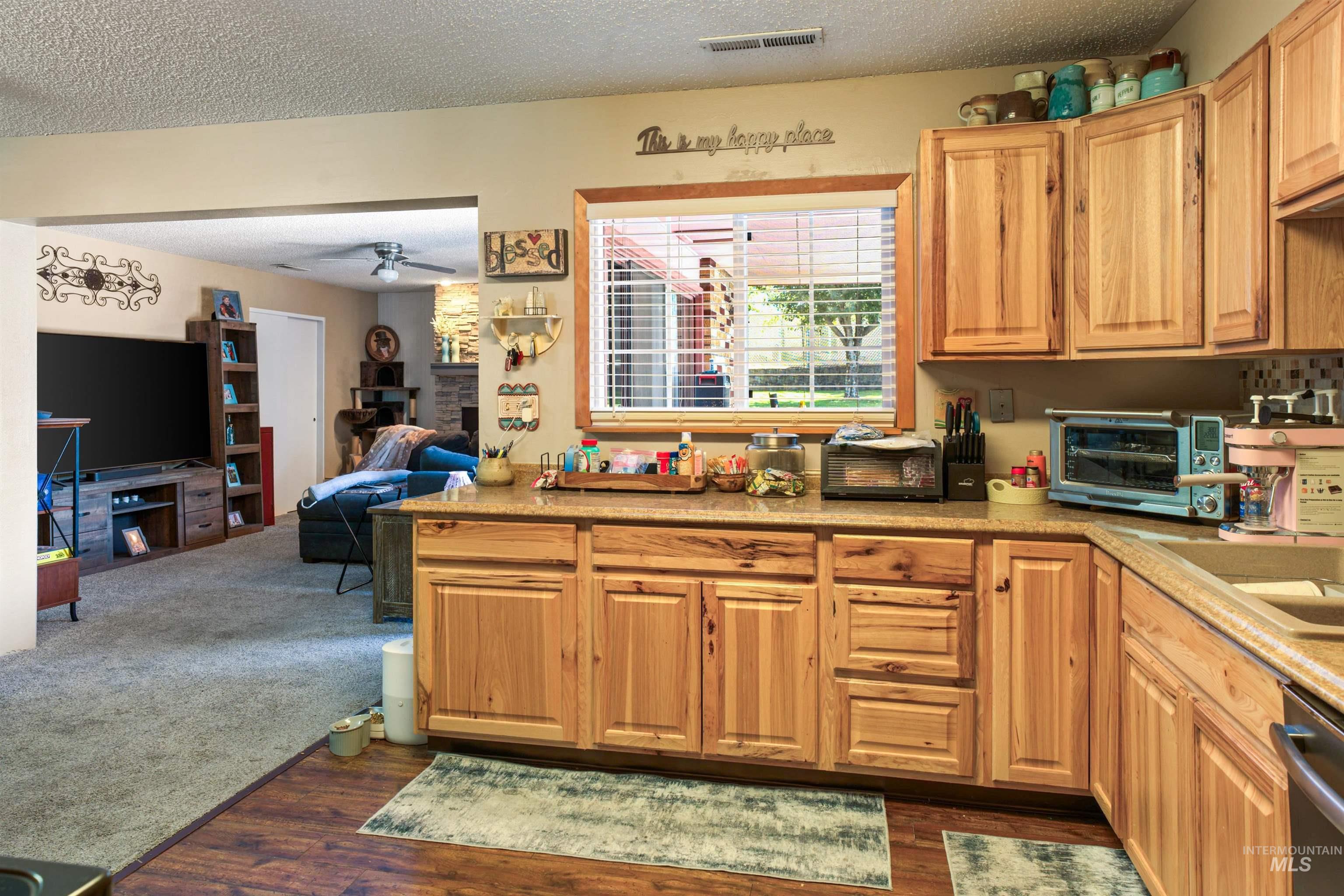 Kitchen featuring wood-finish cabinetry, light-toned countertops, and a window with blinds