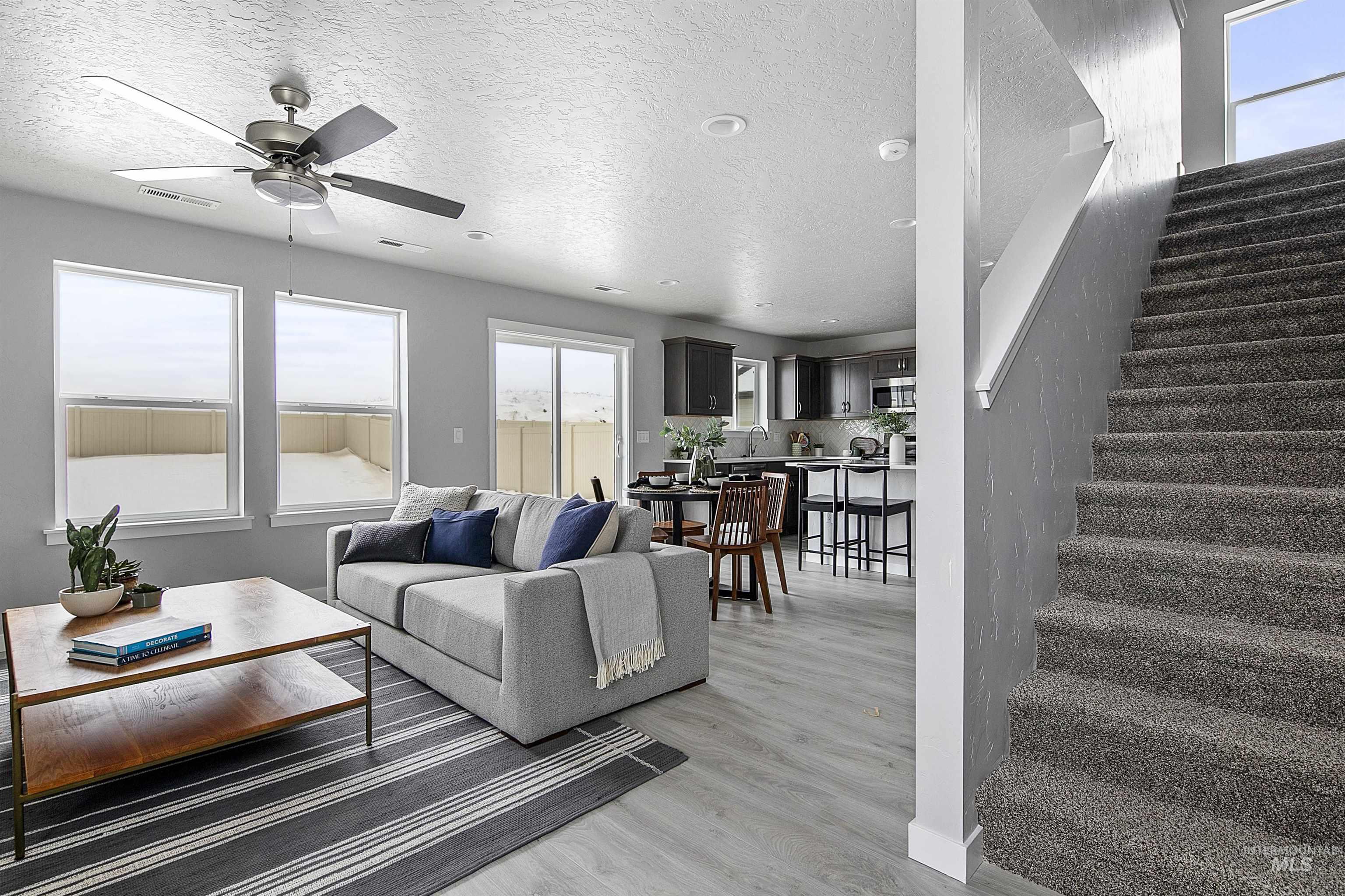 Living area with stairway, a textured ceiling, light wood-type flooring, and a ceiling fan