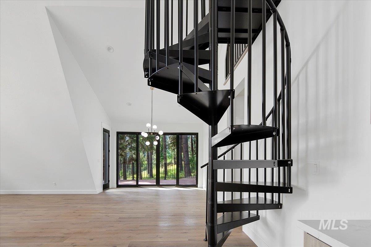 Stairs featuring wood finished floors, a chandelier, and a towering ceiling
