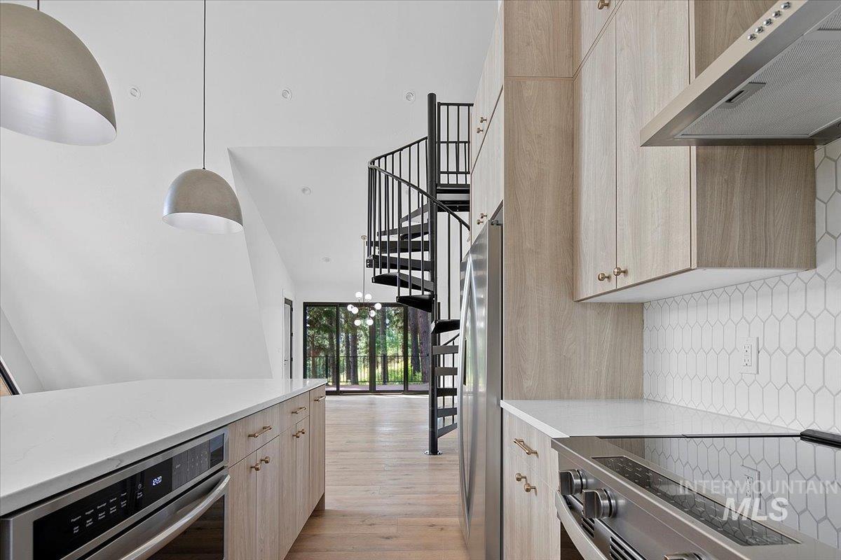 Kitchen featuring ventilation hood, range, light countertops, backsplash, and light wood-style floors