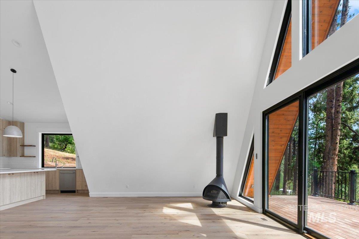 Unfurnished living room with light wood-style flooring and a towering ceiling