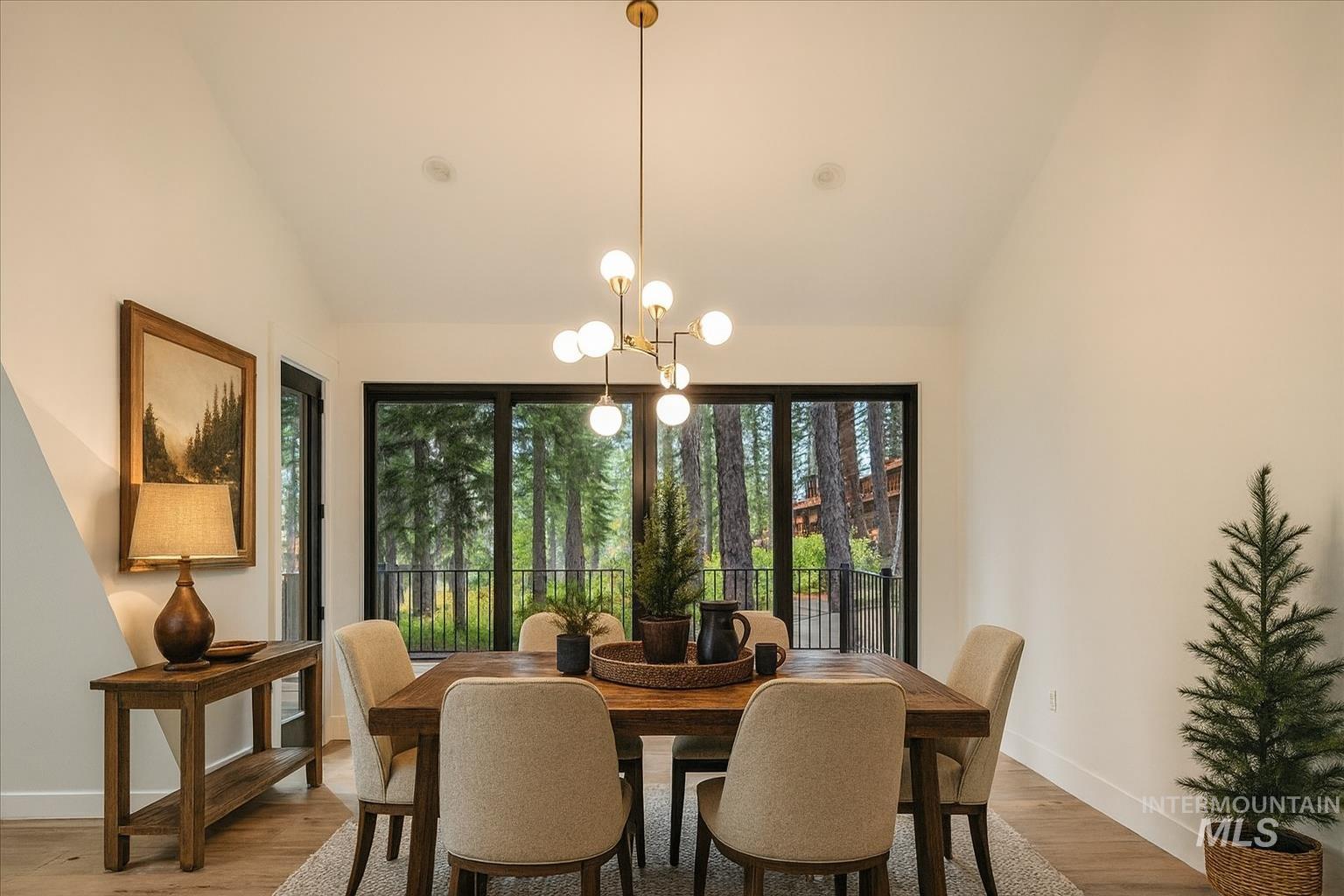 Dining room featuring lofted ceiling, light wood-style floors, and a chandelier