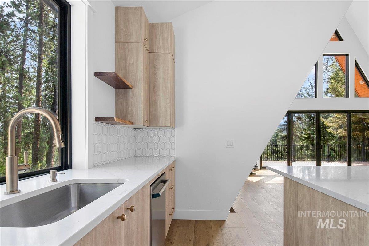 Kitchen with light brown cabinets, open shelves, modern cabinets, and light stone counters