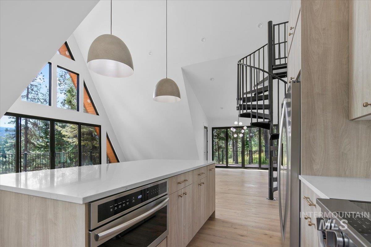 Kitchen with a high ceiling, appliances with stainless steel finishes, light wood-style flooring, light countertops, and modern cabinets