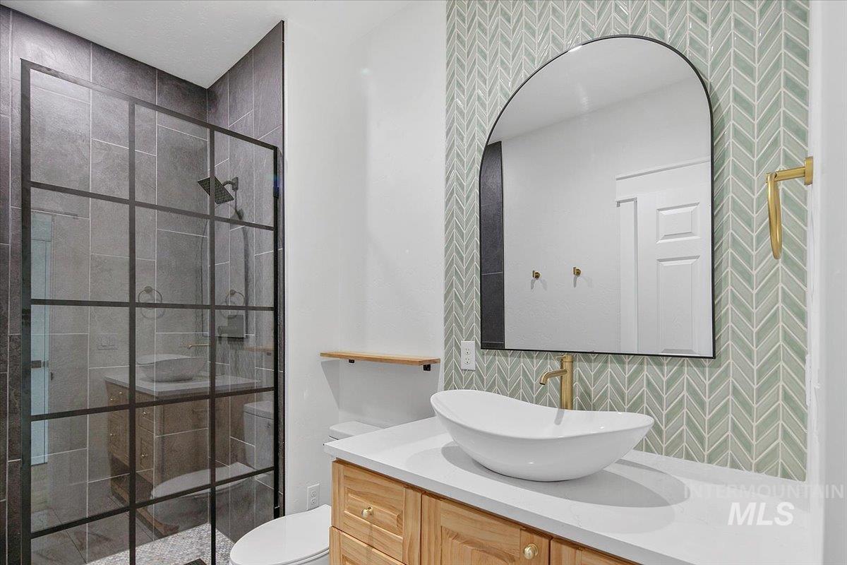 Full bath with a shower stall, vanity, and decorative backsplash