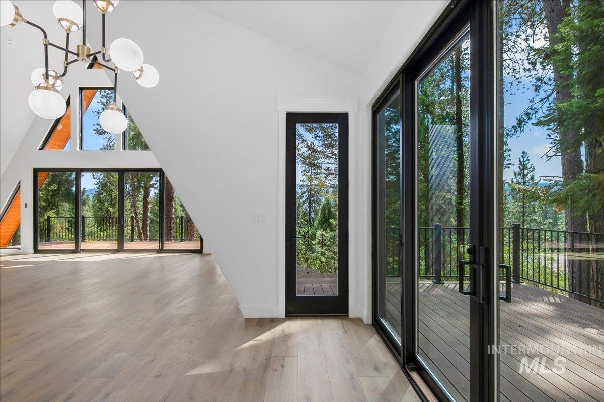 Entrance foyer with wood finished floors, a chandelier, healthy amount of natural light, and high vaulted ceiling